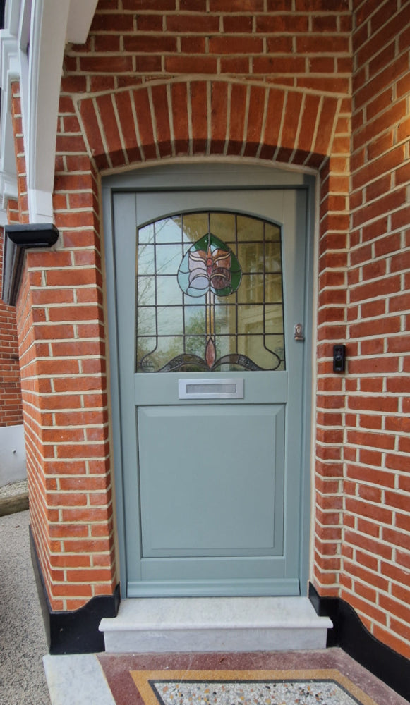 A 1930's style light blue-grey front door with a decorative stained glass panel